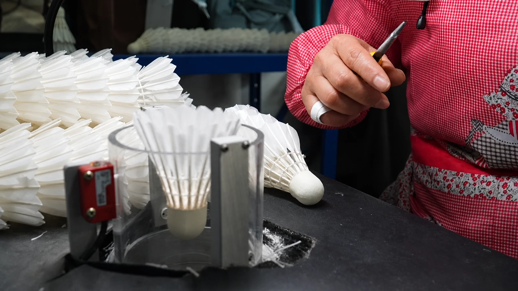 Worker checking shuttlecocks on a badminton flight-testing machine