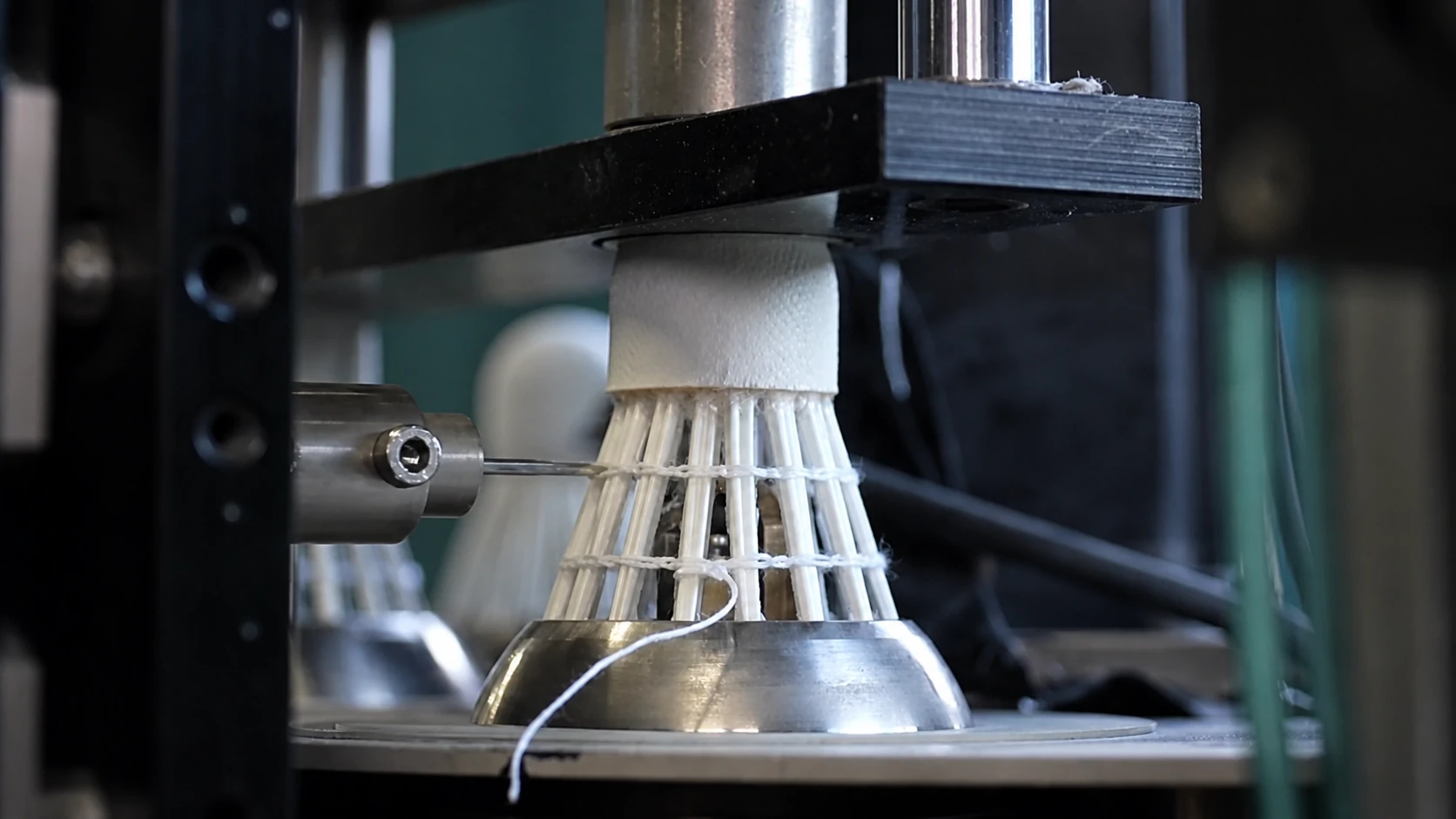 Shuttlecock held in a precision assembly press during thread binding